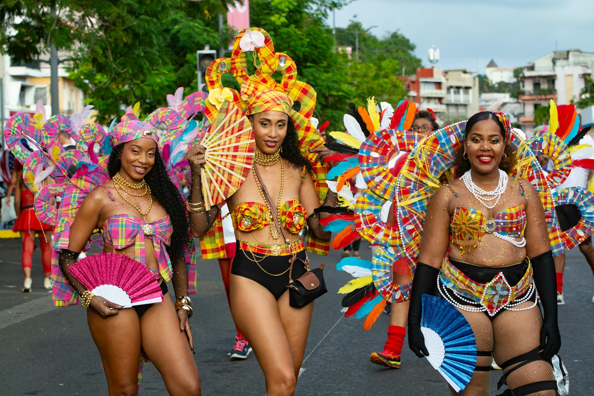 Festive carnival parade featuring vibrant costumes and smiling participants on a lively street.