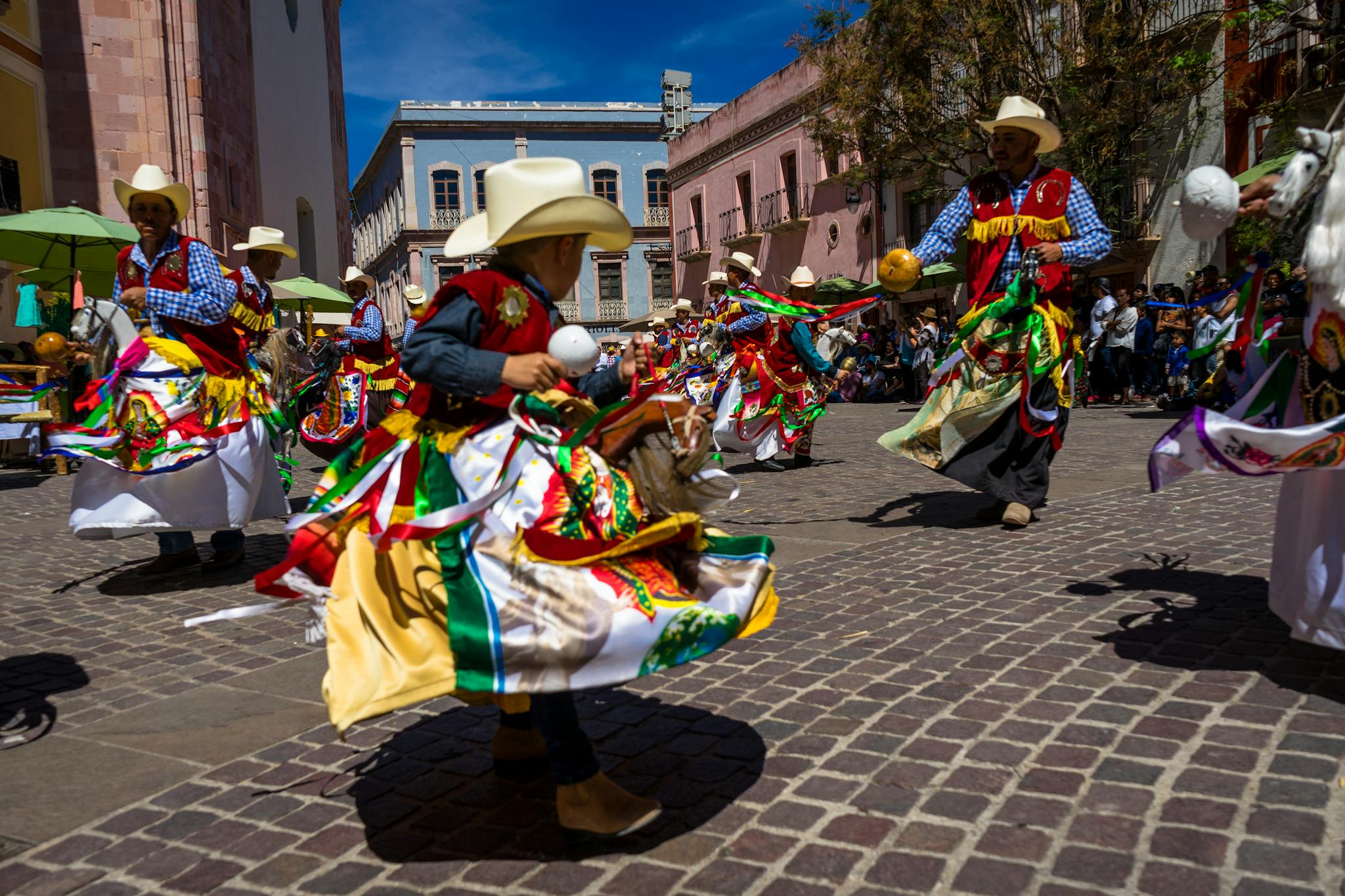 Vivid street performance of traditional dancers in colorful attire celebrating a cultural festival.